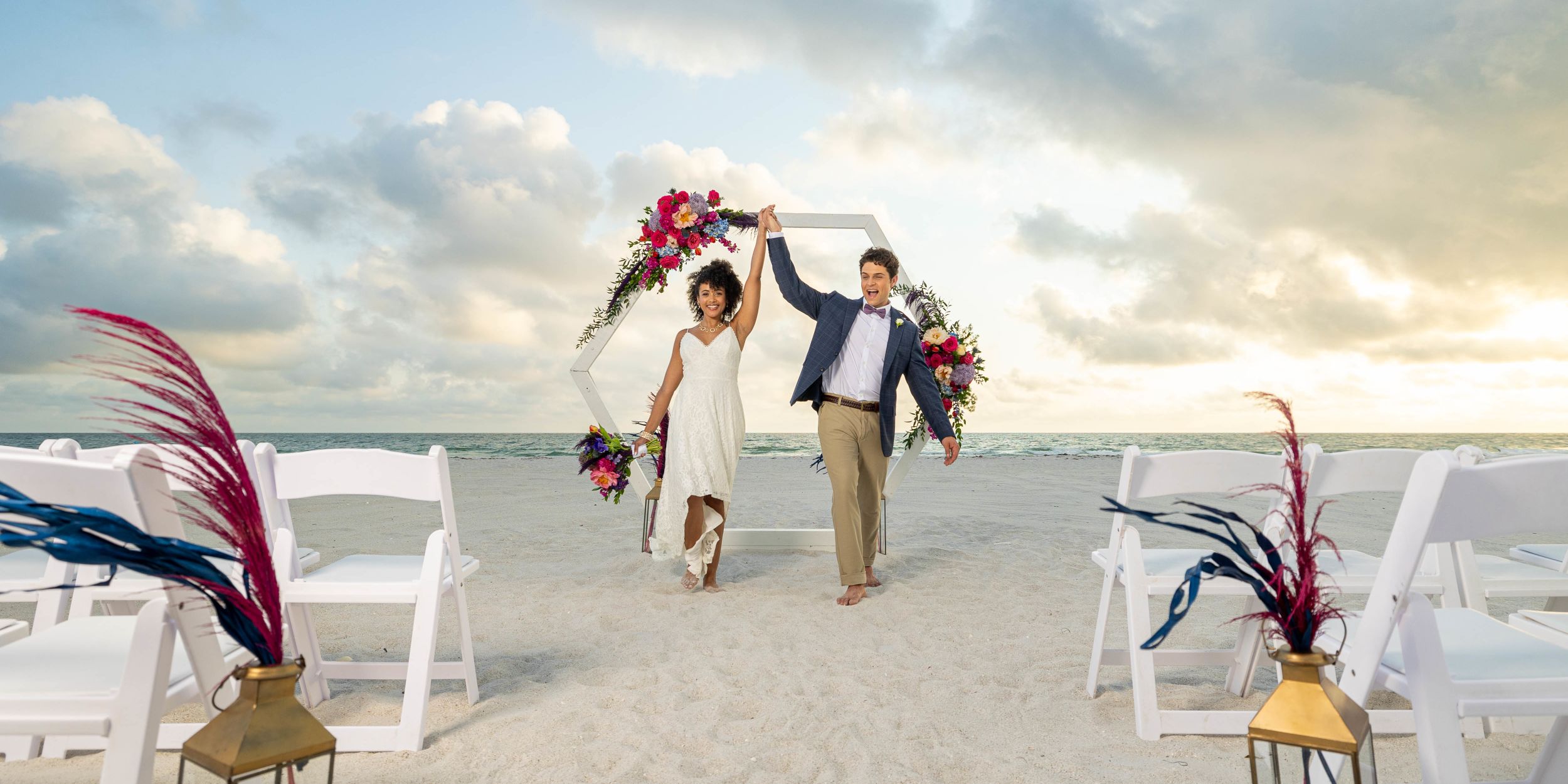 A Man And Woman Holding Flowers On A Beach